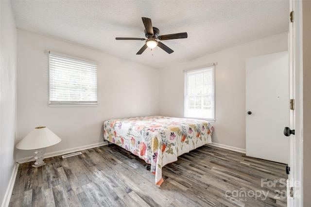 bedroom featuring dark wood-type flooring, multiple windows, and ceiling fan