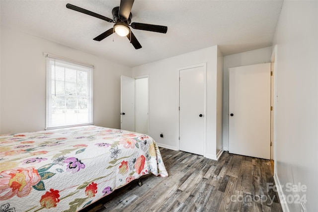 bedroom with ceiling fan, a textured ceiling, and dark hardwood / wood-style flooring