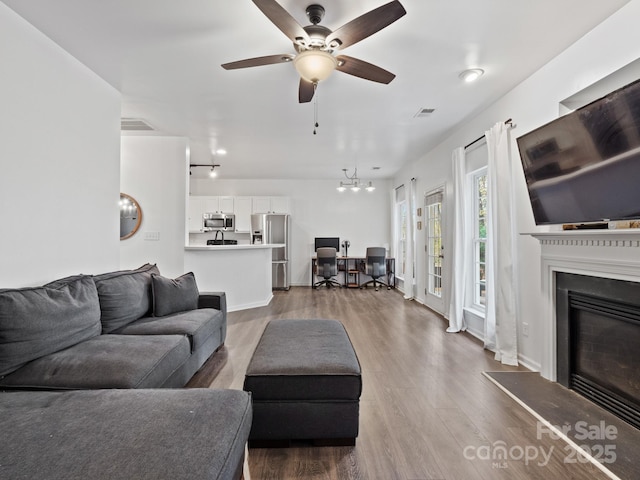 living room with ceiling fan with notable chandelier and hardwood / wood-style flooring