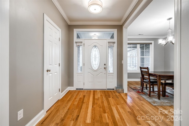 foyer entrance with hardwood / wood-style flooring, crown molding, and a notable chandelier