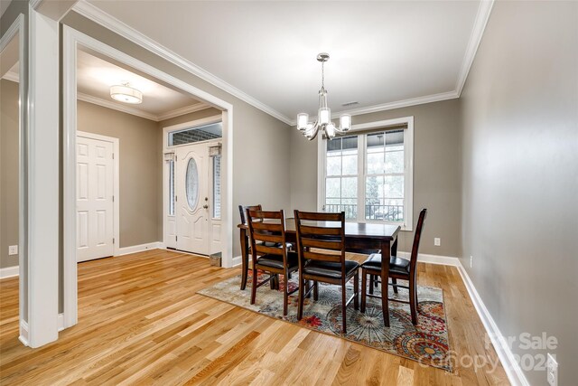 dining area featuring an inviting chandelier, light hardwood / wood-style flooring, and ornamental molding