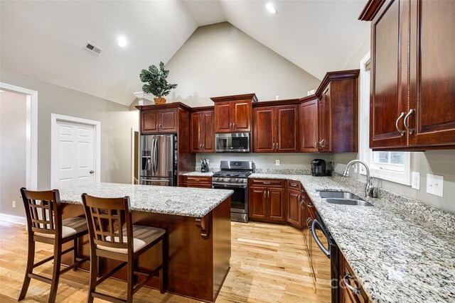 kitchen featuring stainless steel appliances, a kitchen island, light wood-type flooring, sink, and a breakfast bar