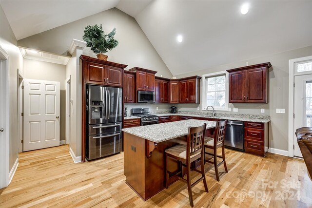 kitchen featuring a kitchen bar, light hardwood / wood-style flooring, sink, a kitchen island, and appliances with stainless steel finishes