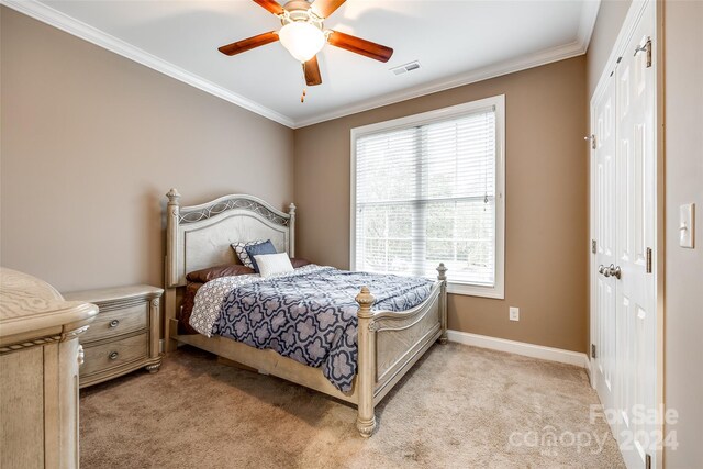 bedroom featuring ceiling fan, light carpet, a closet, and ornamental molding