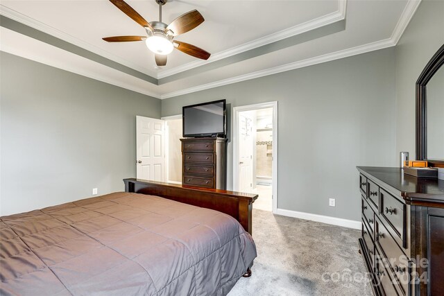 bedroom featuring ensuite bath, ornamental molding, ceiling fan, carpet flooring, and a tray ceiling