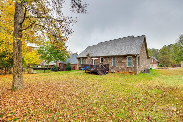 rear view of house with a deck, central AC, and a yard