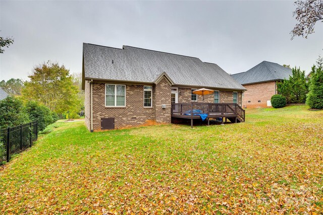 rear view of house featuring a wooden deck and a yard