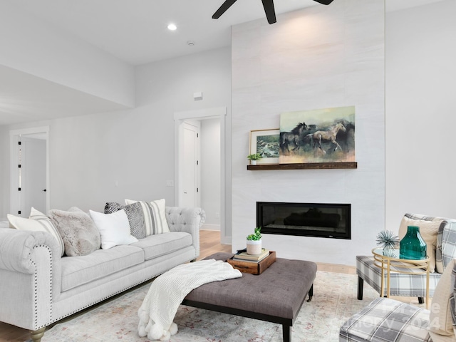 living room featuring ceiling fan, a fireplace, and hardwood / wood-style floors