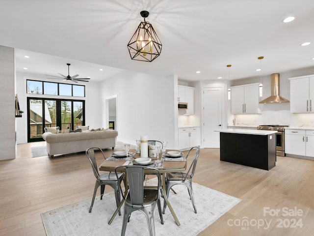 dining space featuring ceiling fan with notable chandelier, light hardwood / wood-style floors, and french doors