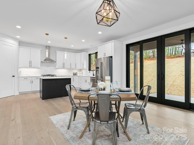 dining space with an inviting chandelier, light wood-type flooring, and french doors