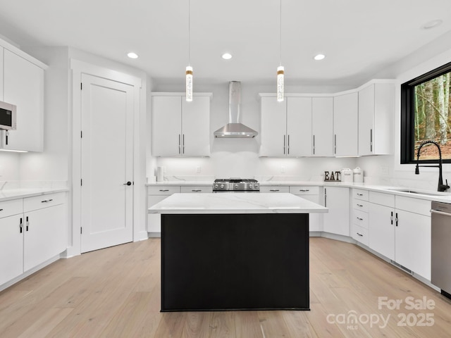 kitchen featuring a kitchen island, pendant lighting, sink, white cabinets, and wall chimney exhaust hood