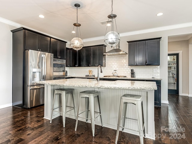 kitchen featuring an island with sink, dark wood-type flooring, decorative light fixtures, and appliances with stainless steel finishes