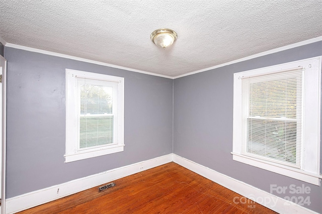 spare room with a textured ceiling, hardwood / wood-style floors, and crown molding