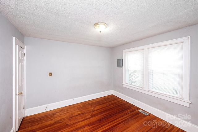 empty room with hardwood / wood-style floors and a textured ceiling