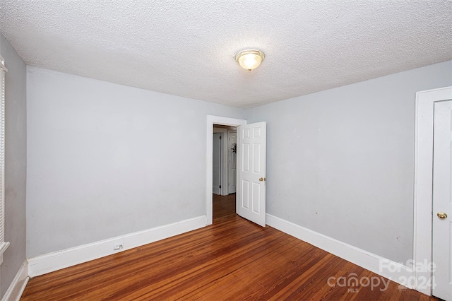 unfurnished room with a textured ceiling and hardwood / wood-style flooring