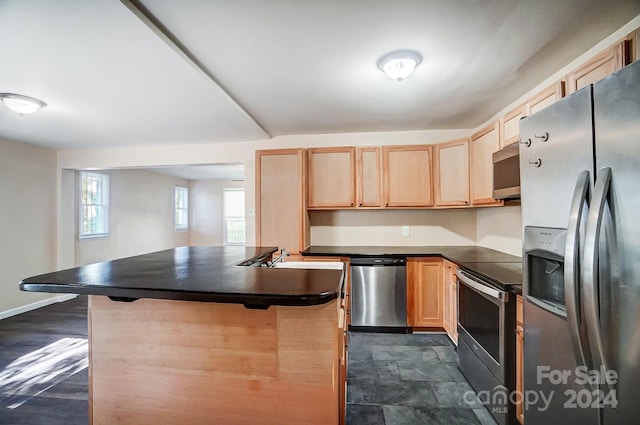 kitchen with stainless steel appliances, sink, a breakfast bar, light brown cabinets, and dark hardwood / wood-style floors