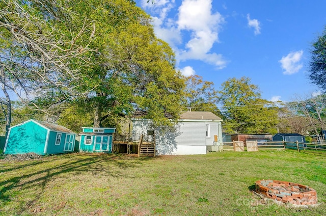 view of yard with a wooden deck, a fire pit, and a storage shed