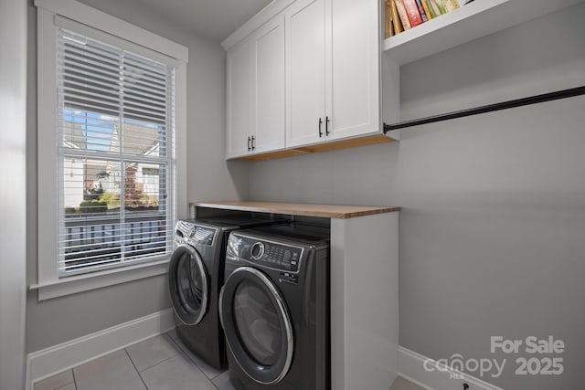 clothes washing area featuring cabinets, light tile patterned floors, and washing machine and clothes dryer