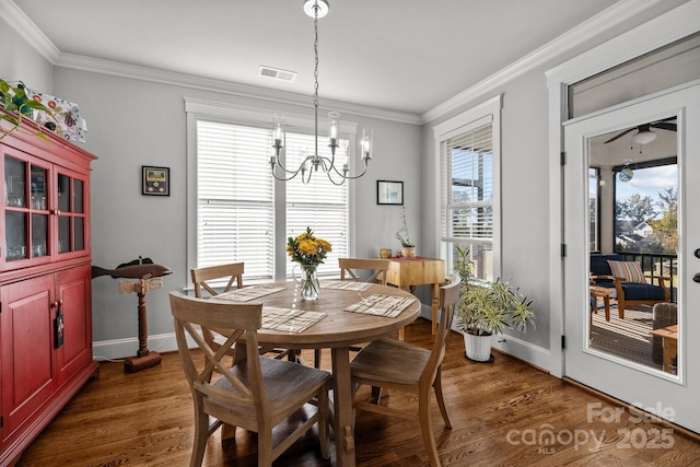 dining area with dark hardwood / wood-style flooring, crown molding, and ceiling fan with notable chandelier