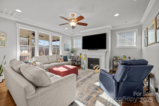 living room with ceiling fan, ornamental molding, hardwood / wood-style floors, and a high end fireplace