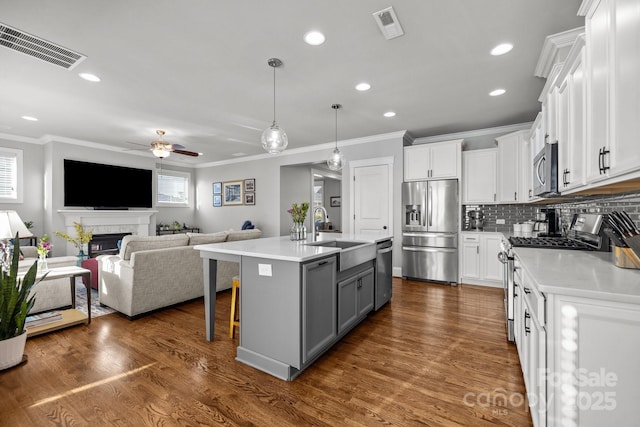 kitchen with gray cabinets, pendant lighting, white cabinets, a kitchen island with sink, and stainless steel appliances