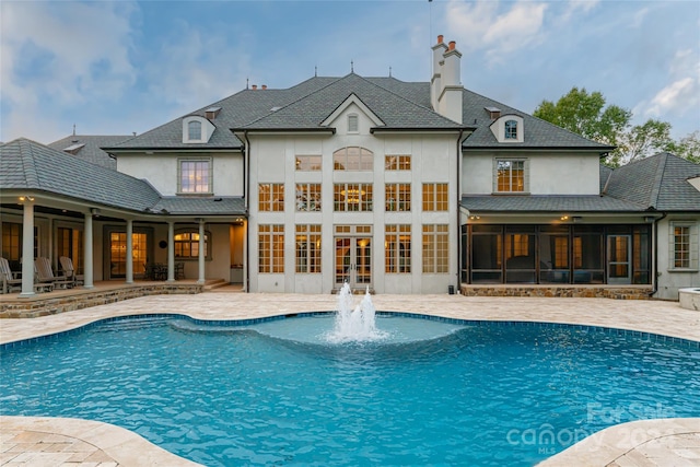 view of swimming pool with pool water feature, a sunroom, and a patio area