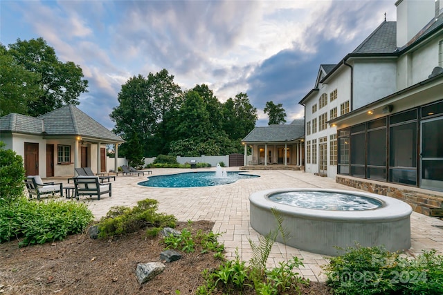 view of swimming pool featuring a sunroom, pool water feature, an in ground hot tub, and a patio area