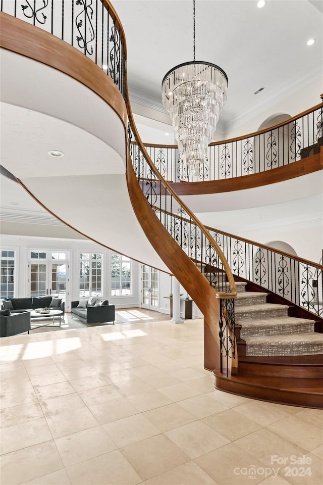 staircase featuring ornamental molding, a notable chandelier, tile patterned floors, and a high ceiling