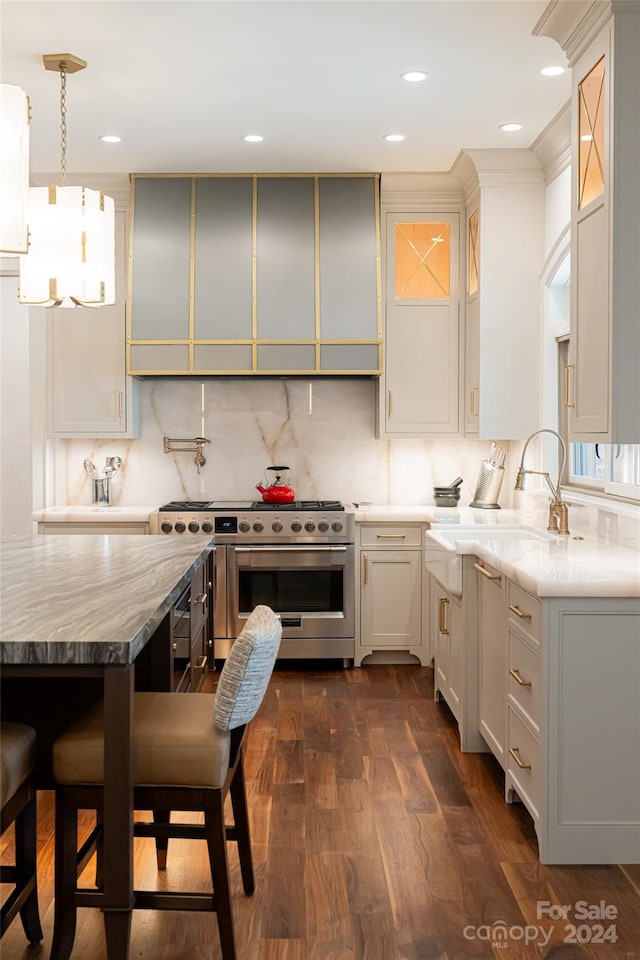 kitchen featuring tasteful backsplash, dark hardwood / wood-style floors, pendant lighting, high end stove, and white cabinetry