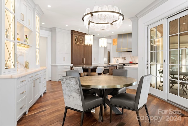 dining area with dark wood-type flooring, a chandelier, and ornamental molding