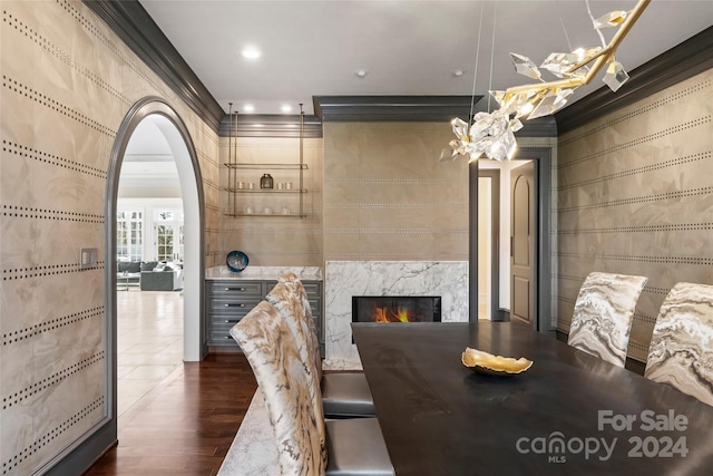 dining space with dark wood-type flooring, a fireplace, and ornamental molding