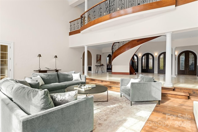 living room featuring decorative columns, wood-type flooring, and a high ceiling