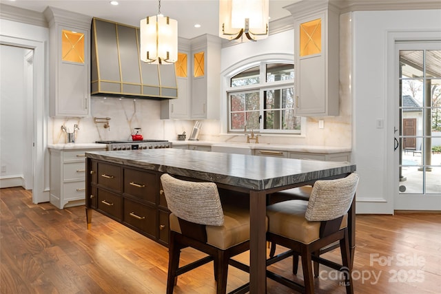 kitchen with pendant lighting, dark wood-type flooring, backsplash, white cabinets, and custom exhaust hood