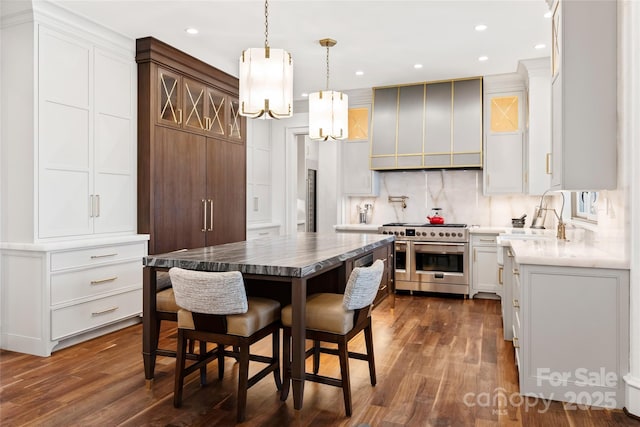 kitchen with wall chimney exhaust hood, a center island, double oven range, decorative backsplash, and white cabinets