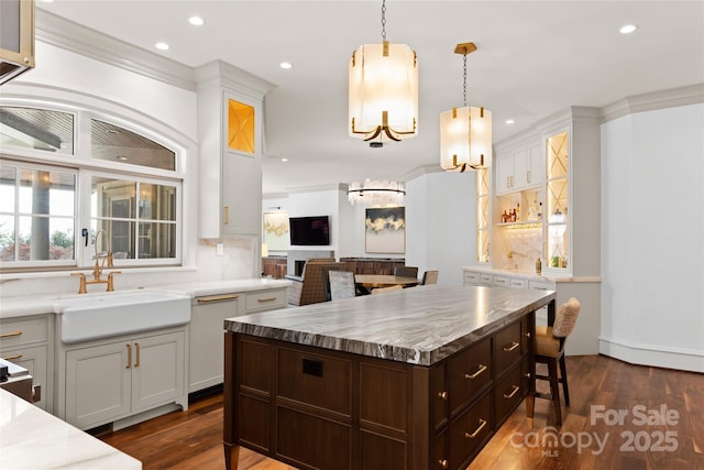 kitchen featuring sink, crown molding, decorative light fixtures, a center island, and dark hardwood / wood-style floors