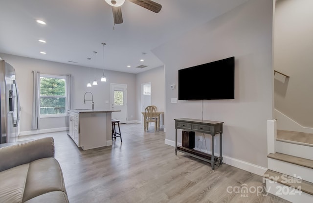 living room with sink, ceiling fan, and light hardwood / wood-style flooring