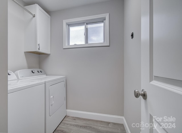 laundry area featuring light wood-type flooring, washing machine and dryer, and cabinets