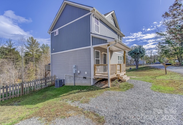 view of side of home with central air condition unit, a porch, and a yard