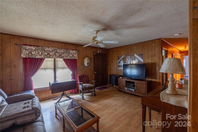 living room with ceiling fan, a textured ceiling, and light hardwood / wood-style floors