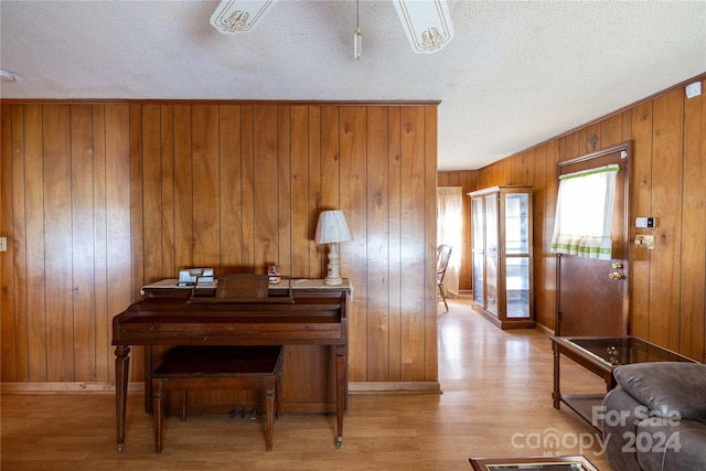 miscellaneous room featuring wood walls, a textured ceiling, and light wood-type flooring