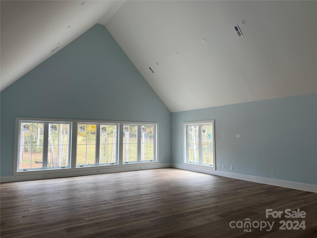 unfurnished living room featuring high vaulted ceiling, dark hardwood / wood-style floors, and a wealth of natural light