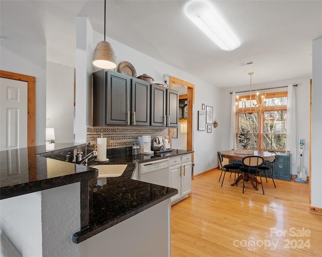 kitchen featuring pendant lighting, backsplash, light wood-type flooring, kitchen peninsula, and a chandelier