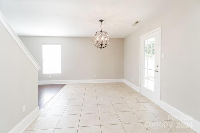 empty room with an inviting chandelier and light tile patterned floors