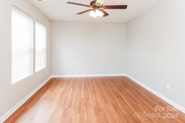 empty room with ceiling fan and light hardwood / wood-style flooring