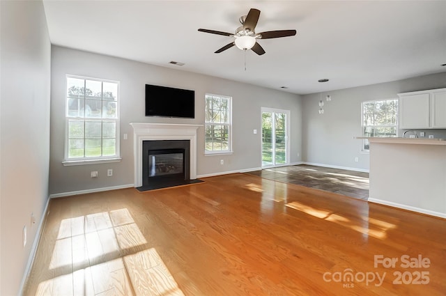 unfurnished living room with light wood-type flooring and ceiling fan