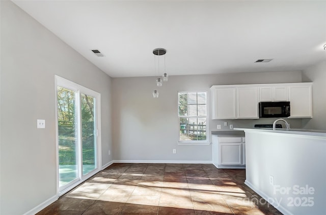 kitchen featuring a healthy amount of sunlight, hanging light fixtures, and white cabinetry