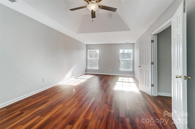 spare room with ceiling fan, dark hardwood / wood-style floors, and a tray ceiling