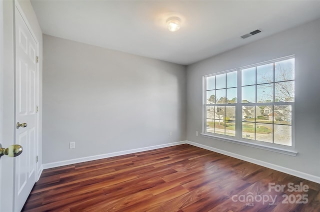 spare room featuring dark wood-type flooring and plenty of natural light