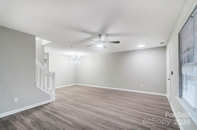 spare room featuring ceiling fan with notable chandelier and wood-type flooring