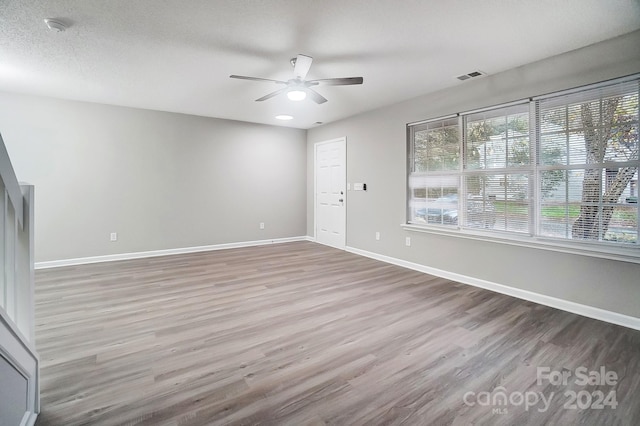 empty room featuring ceiling fan, a textured ceiling, and hardwood / wood-style flooring